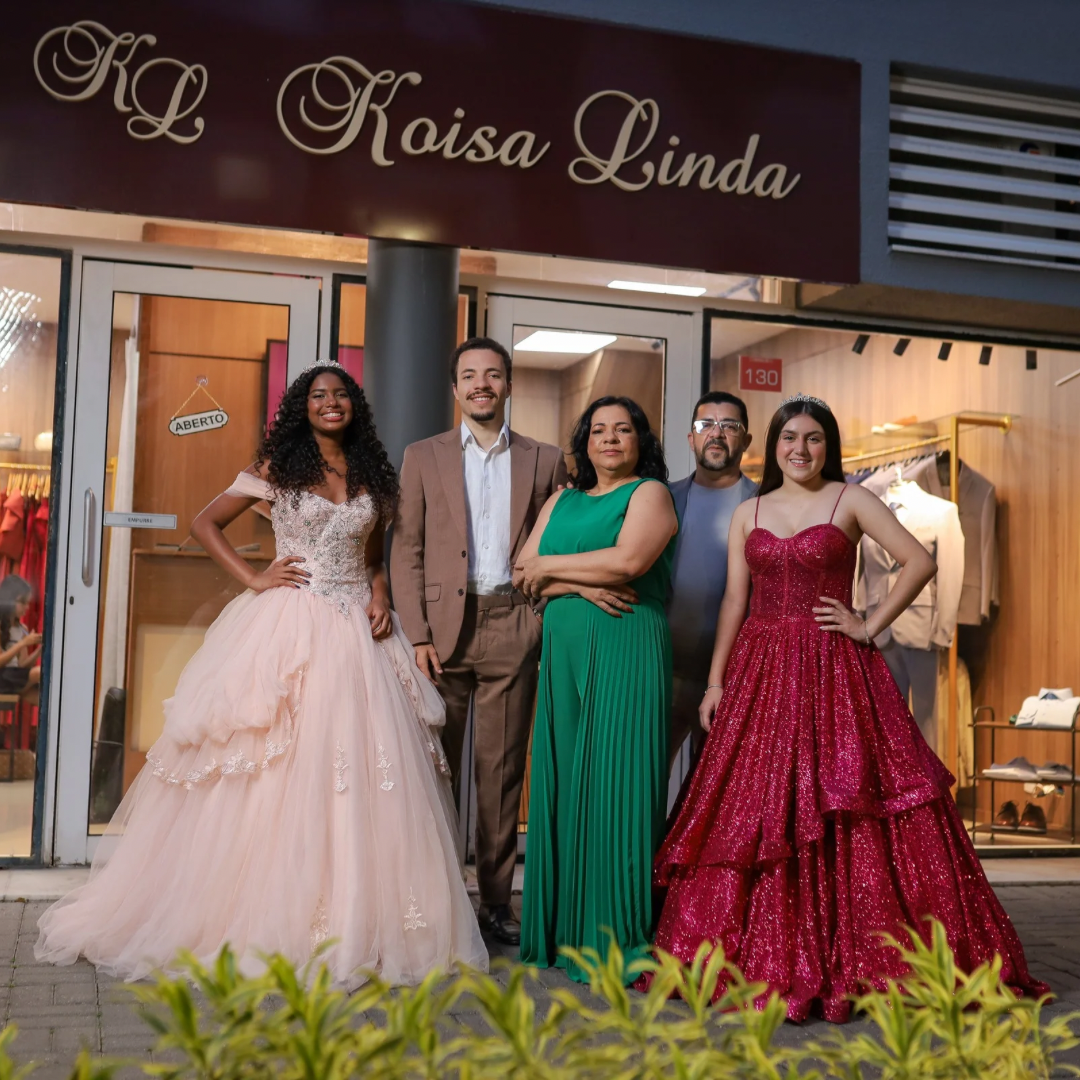 Cinco pessoas reunidas diante da fachada Koisa Linda, com vestidos de festa